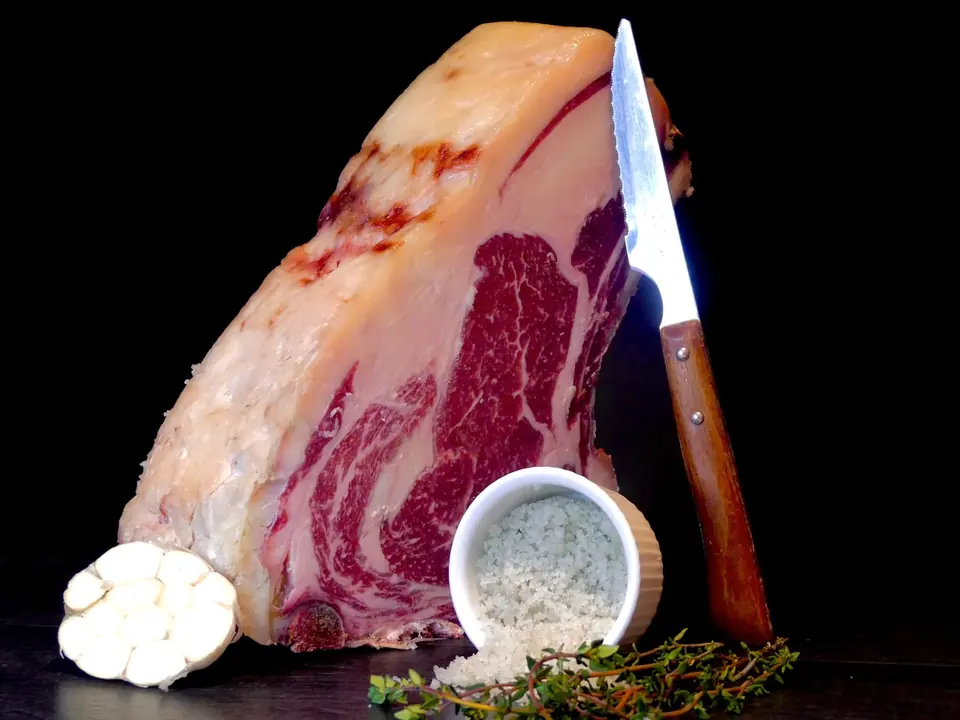 Côte de bœuf, couteau et fleur de sel sur fond noir